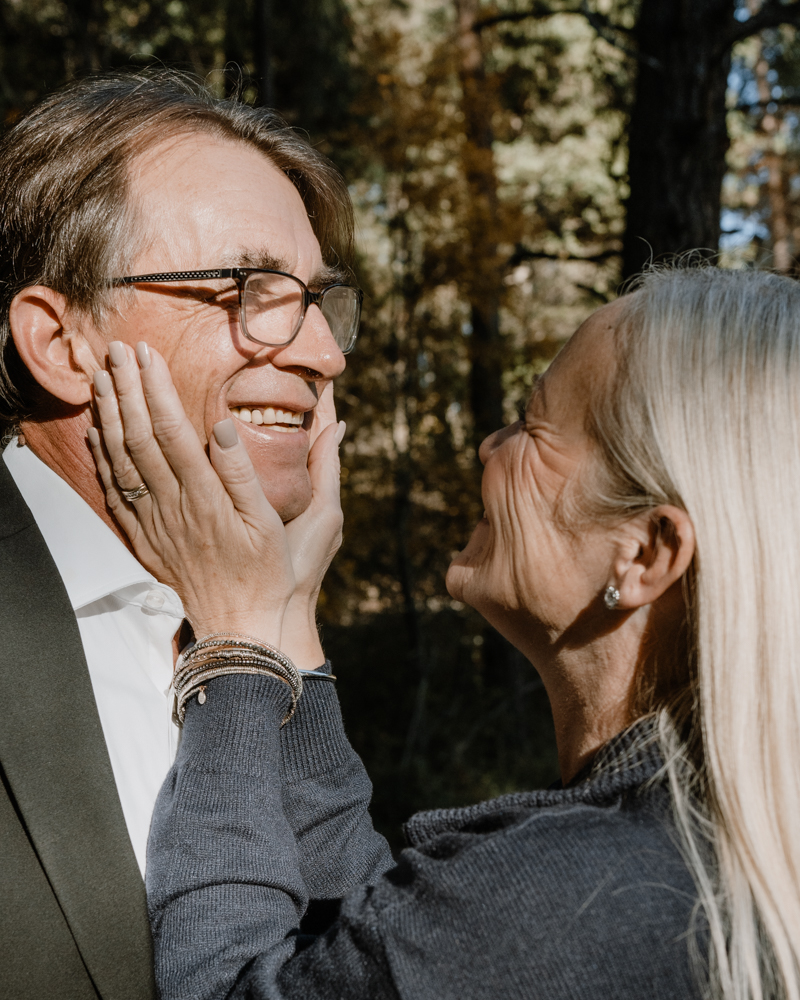 Man and woman smiling at each other as she holds his face in her hands.