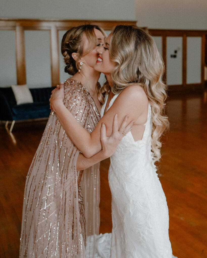 mother and daughter hugging and kissing as the bride prepares for her wedding day.