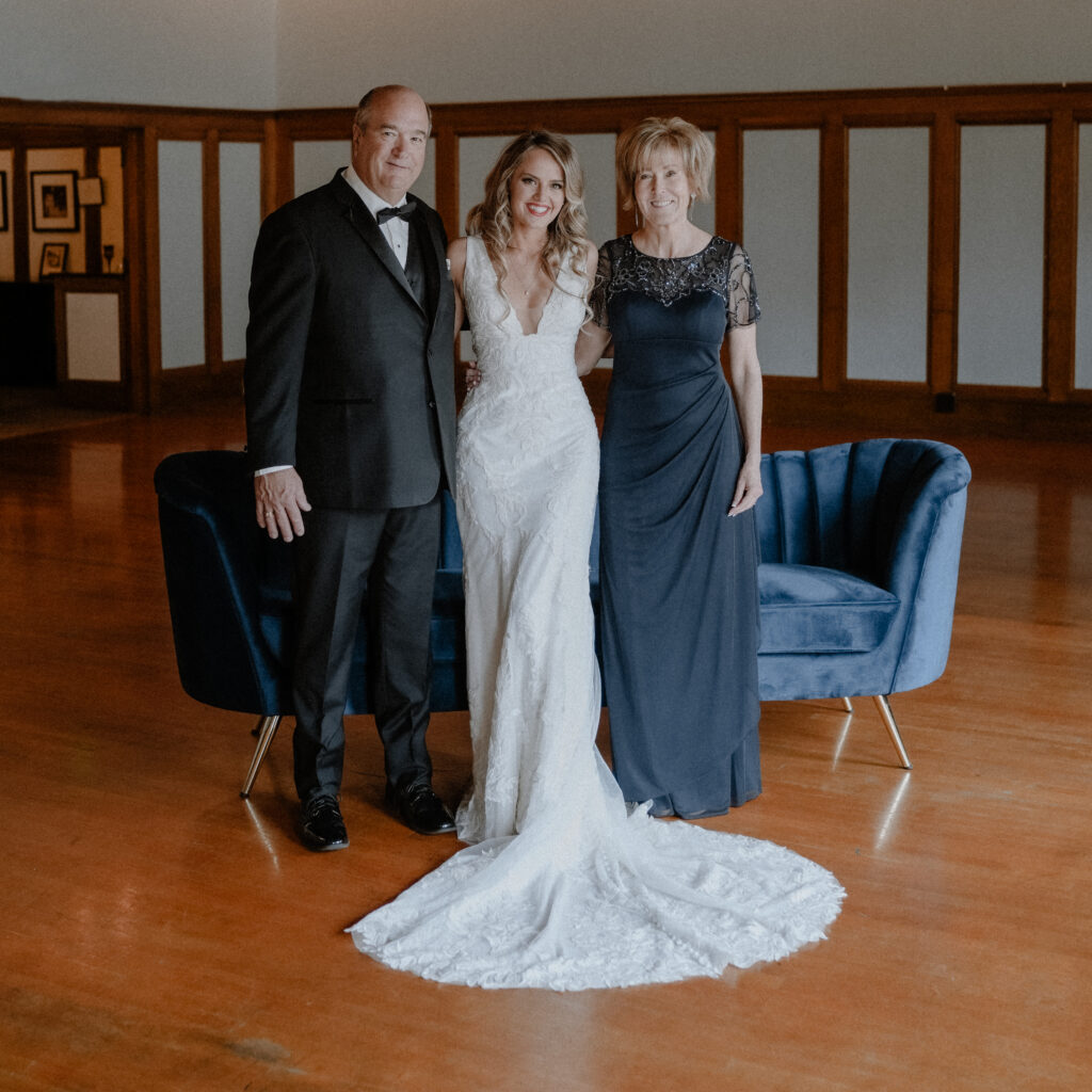 bride standing with her dad and step mom and smiling.