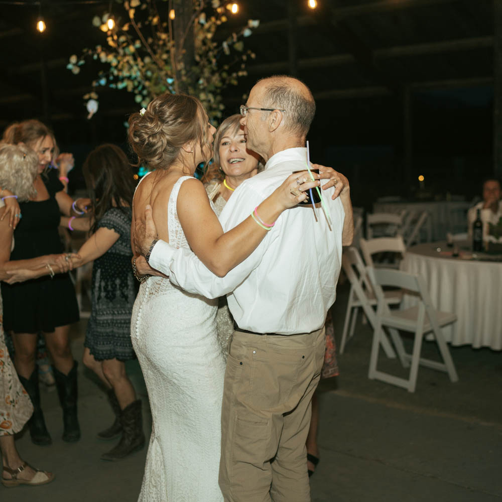 bride hugging and dancing with her parents during the wedding reception.