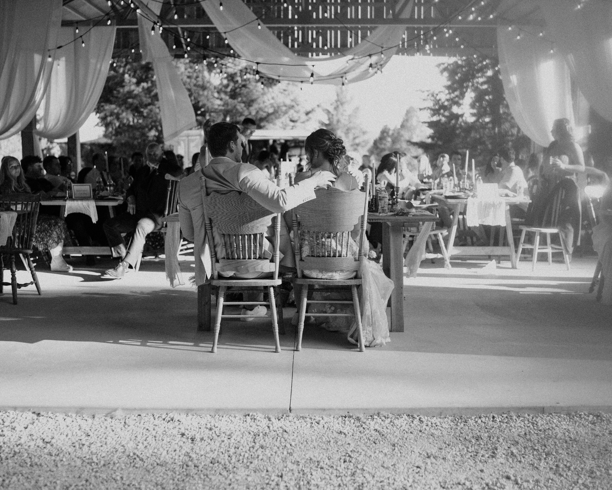 bride and groom sitting at their sweetheart table with arms outstretched