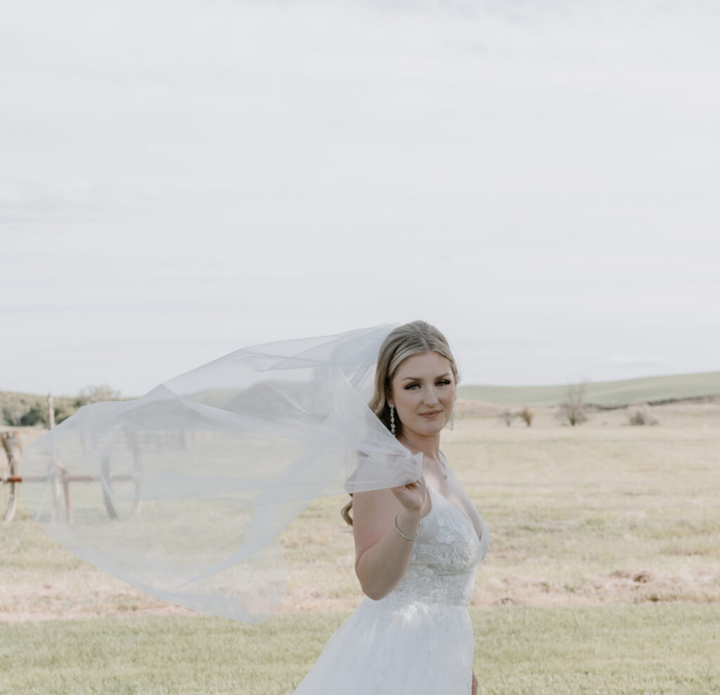 beautiful bride in her wedding dress and holding her veil as it blows in the wind.