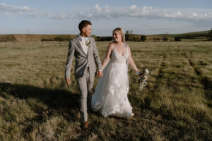 bride and groom holding hands and smiling at each other.