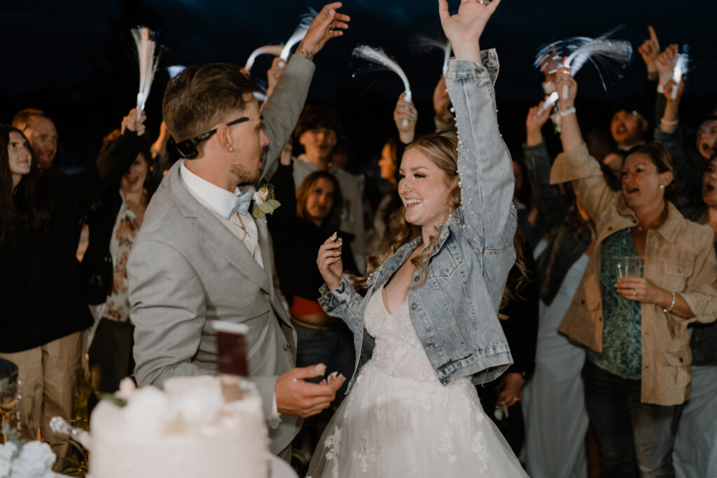 bride and groom cheering with cake on their faces.