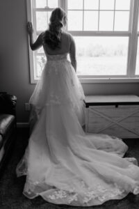 Bride standing at the window looking out in her beautiful wedding dress at the farmhouse wedding in Walla Walla, WA. 