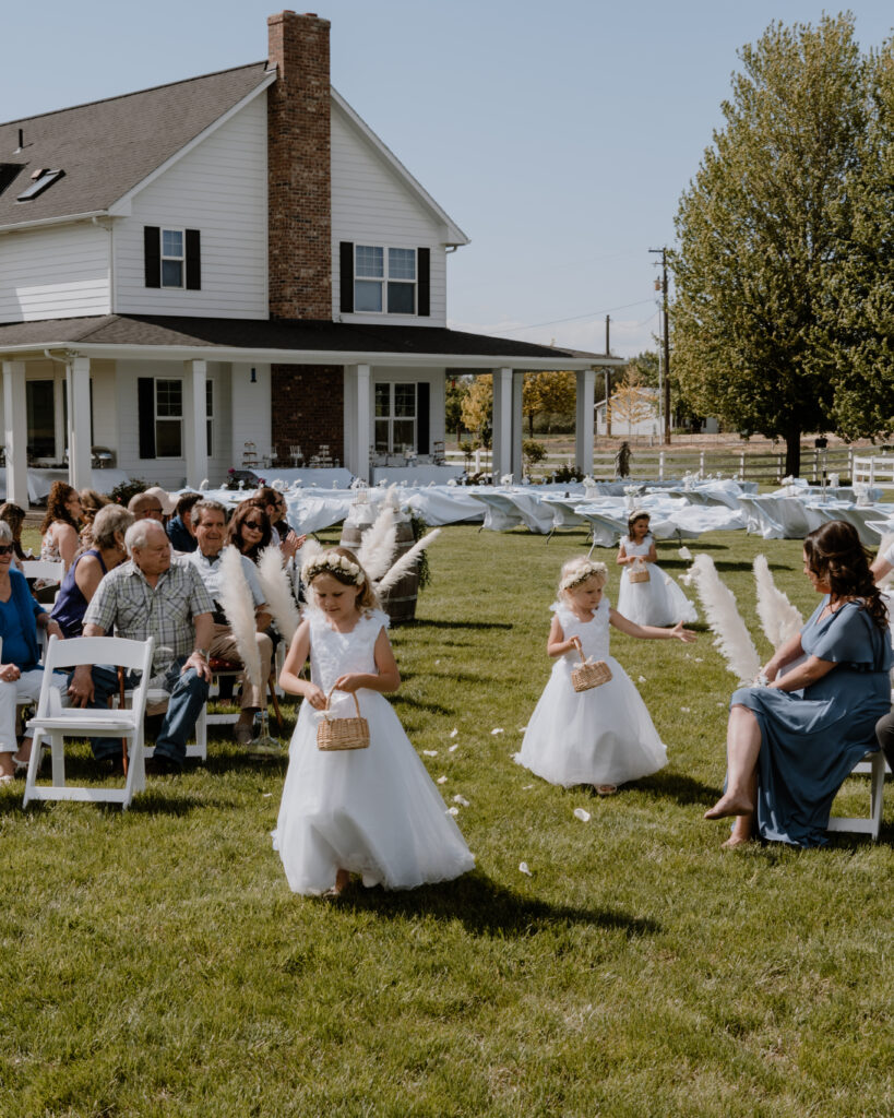 flower girls walking down the aisle through flowers petals.