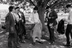 groom and groomsmen standing outside talking as they finish getting ready.