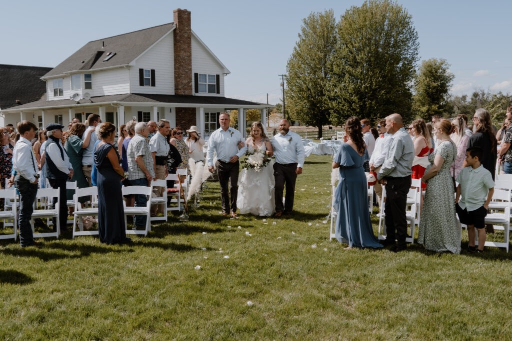 bride walking down aisle with her dad's for the ceremony at the farmhouse wedding in Walla Walla, WA.