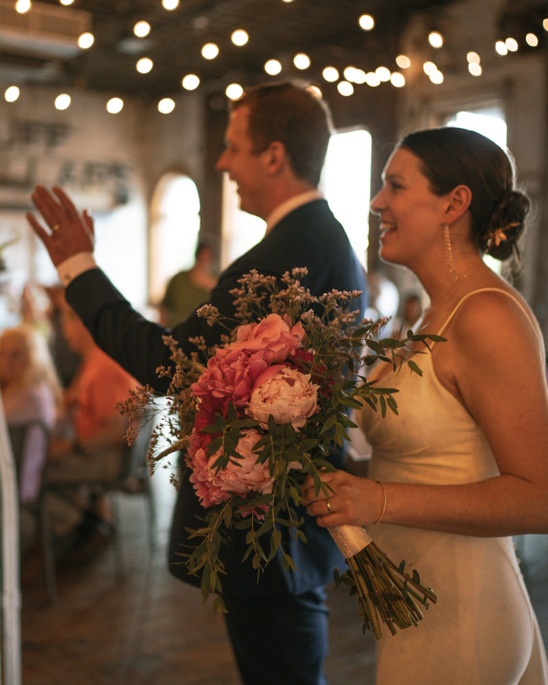 bride and groom smiling and waving to their guests as they entered their intimate reception at Overbluff Cellars. 