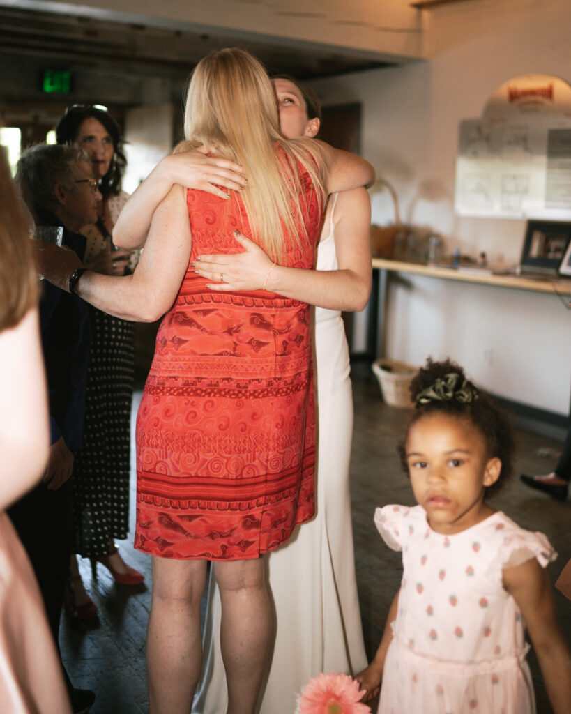 bride hugging a friend at their intimate  wedding reception. 