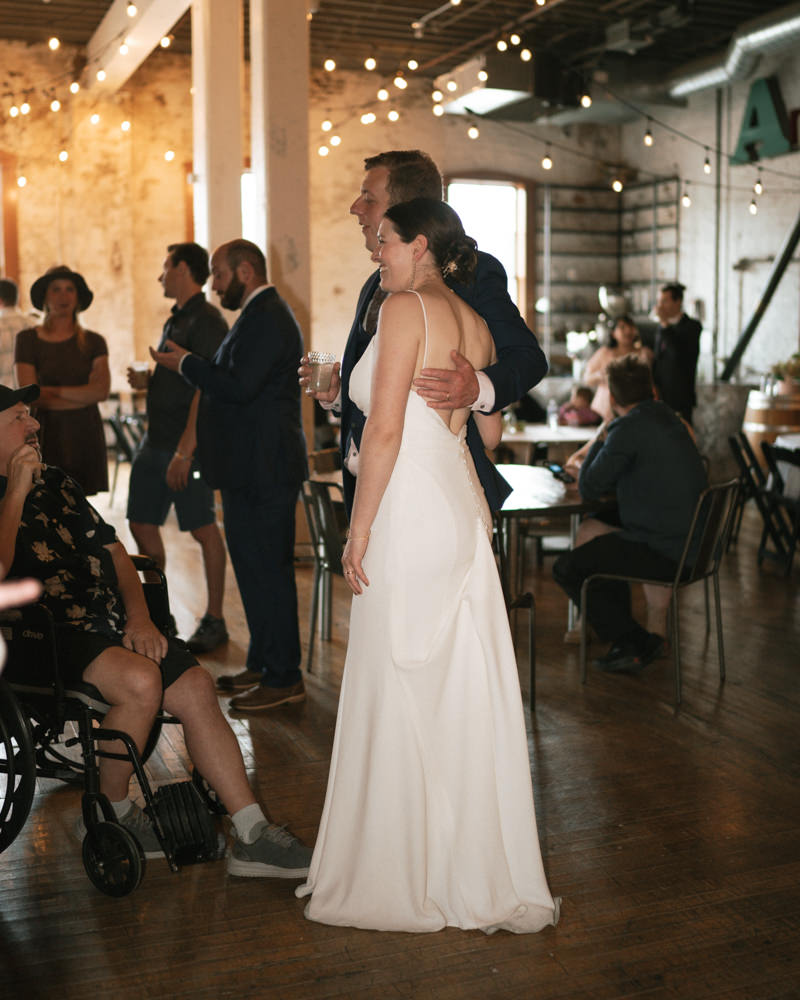 intimate and dreamy bride and groom posing for a photo their friend is taking.