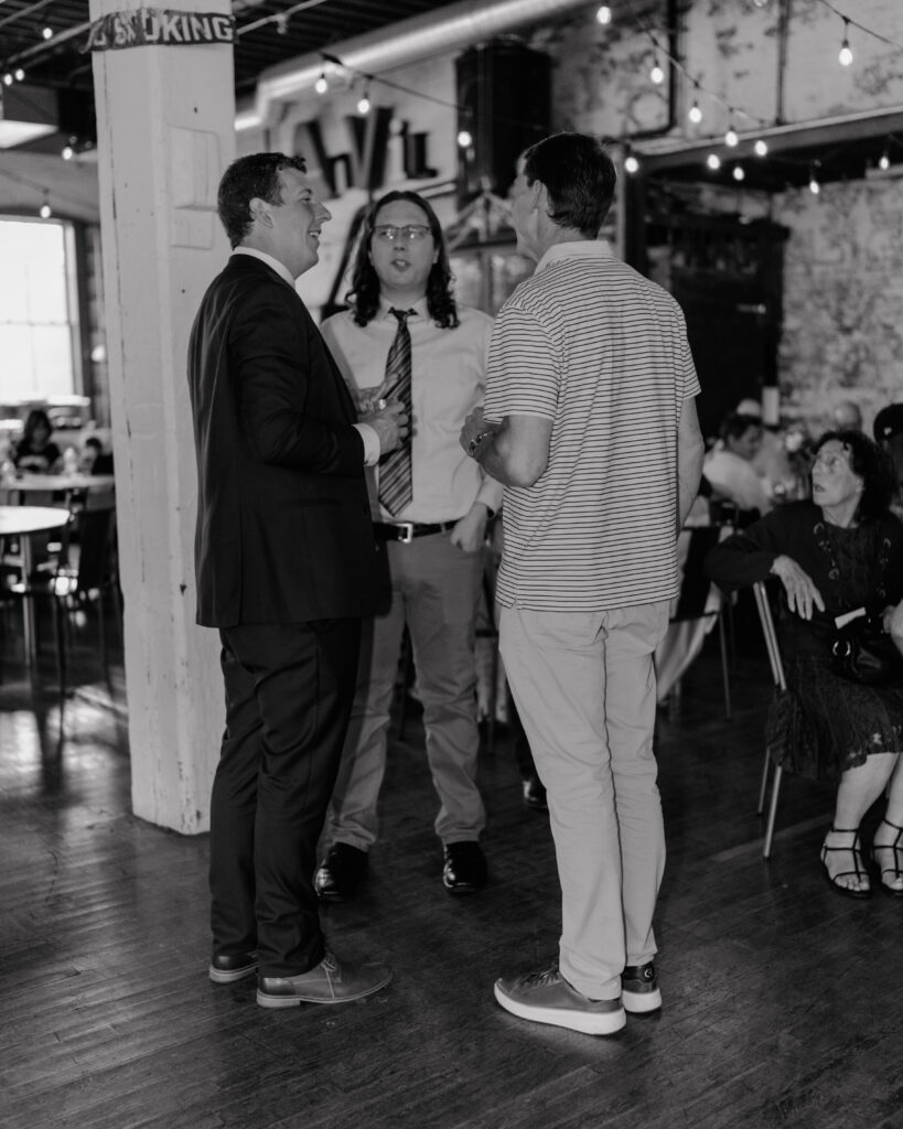 groom and friends talking during the reception at their documentary wedding in Spokane, WA. 