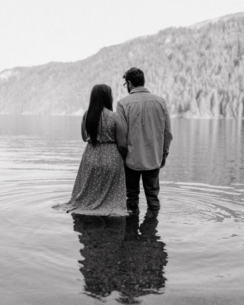 couple holding hands while standing in the water.