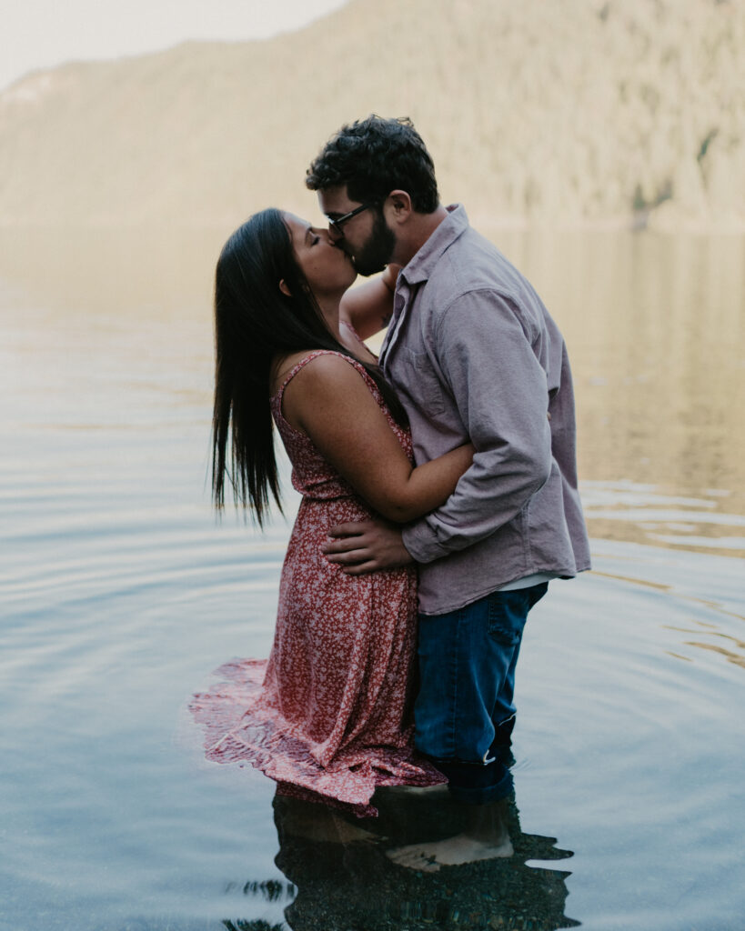 couple kissing and embracing while standing in the water.