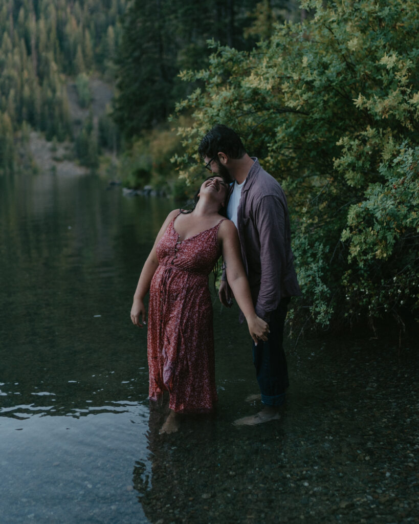 couple holding hands while smiling at each other and standing in water.