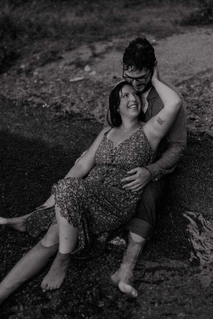 couple embracing and smiling as they sit on the bank or the river