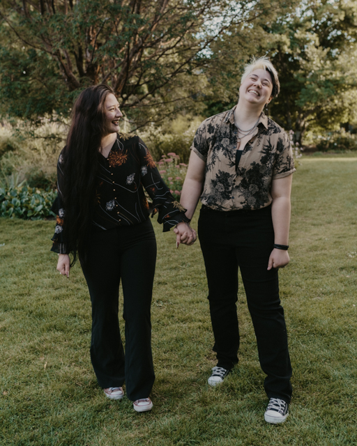 couple walking and holding hands as they laugh in a garden at Manito Park. 