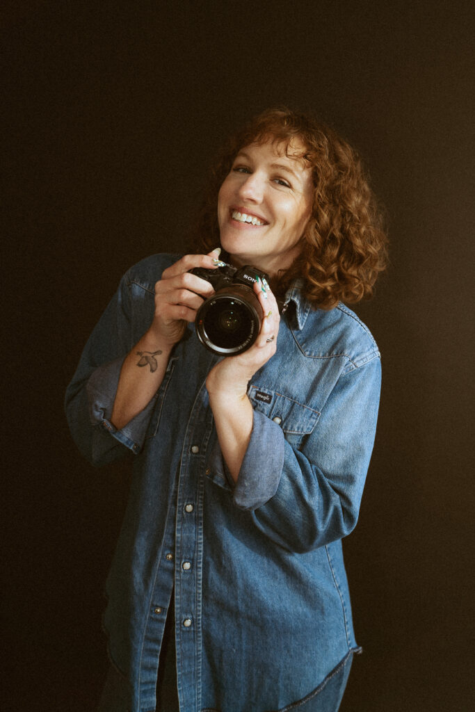 Spokane wedding photographer holding a camera and smiling.