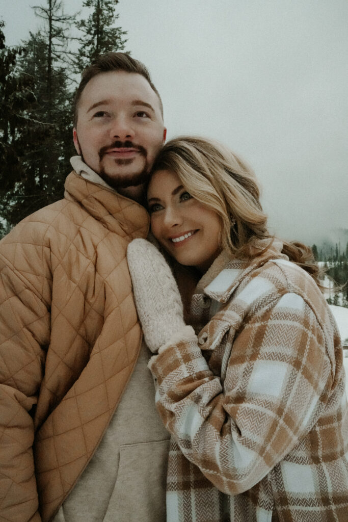 couple cuddling as the look off into the distance.