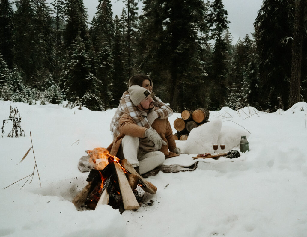 couple sitting by a fire hugging each other.