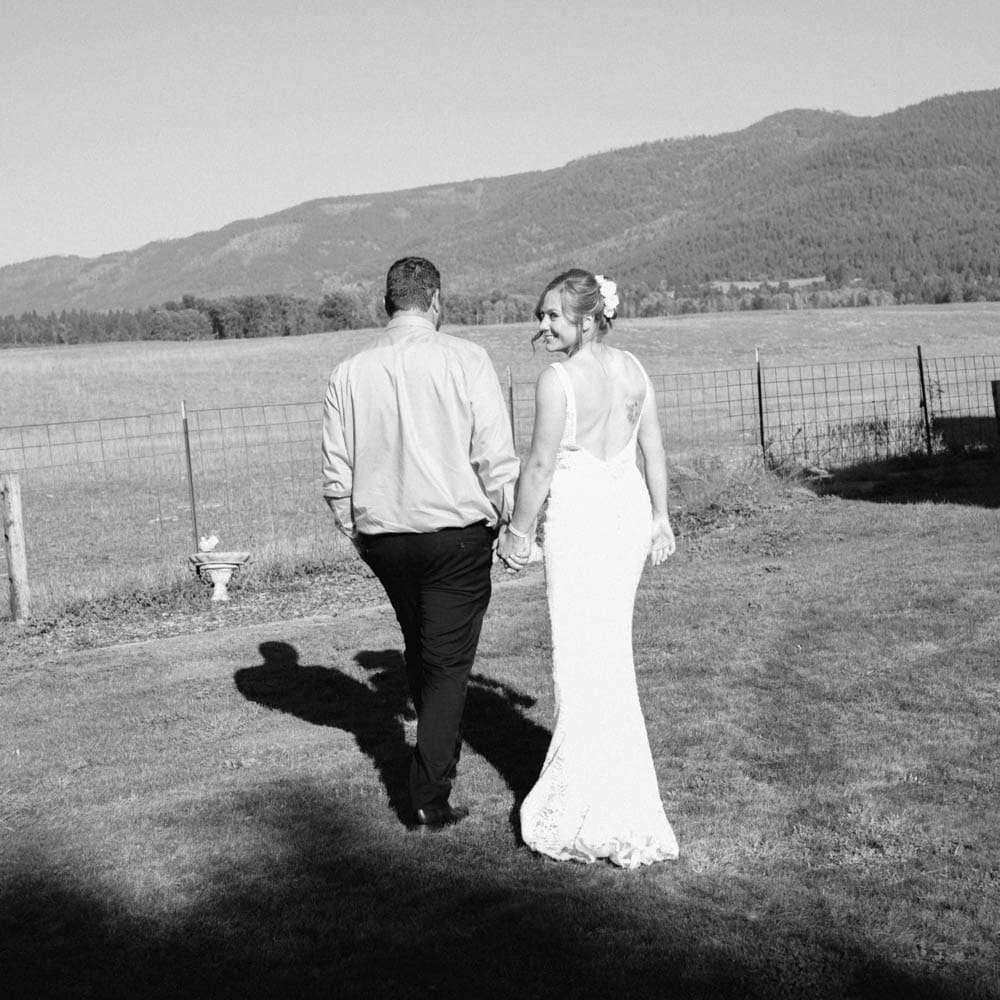 bride and groom walking into the sunlight as the bride looks behind her.