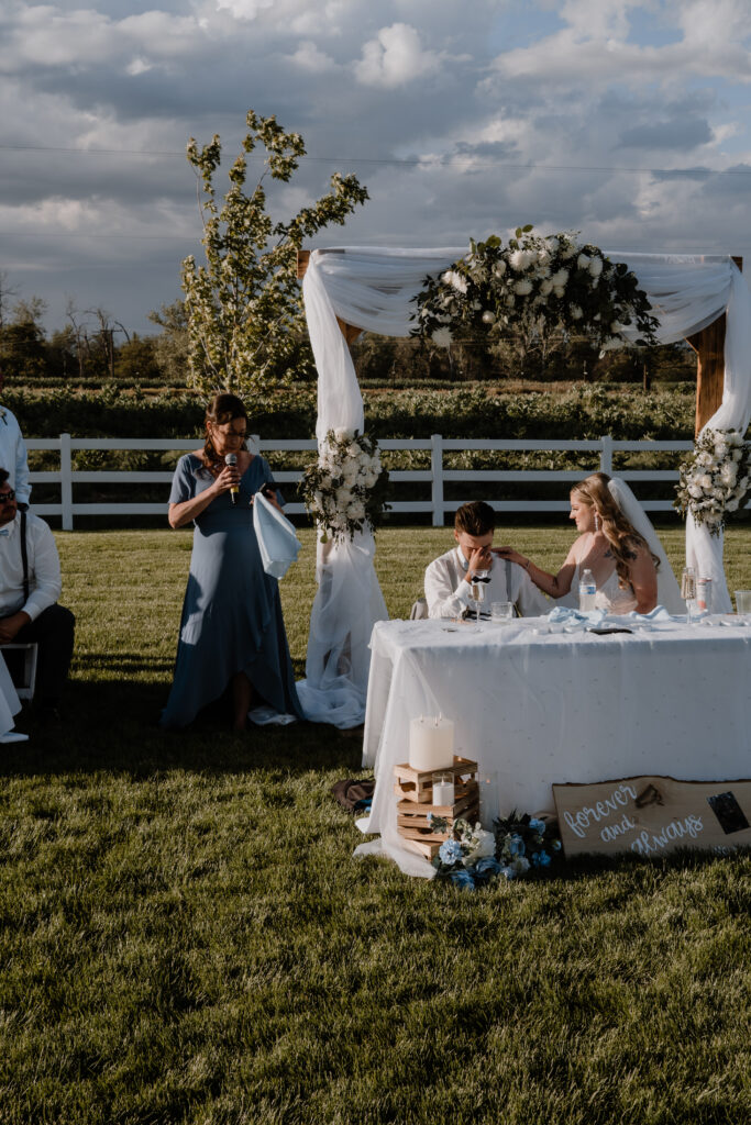 bride consoling her new husband as the grooms mom reads her emotional speech.   