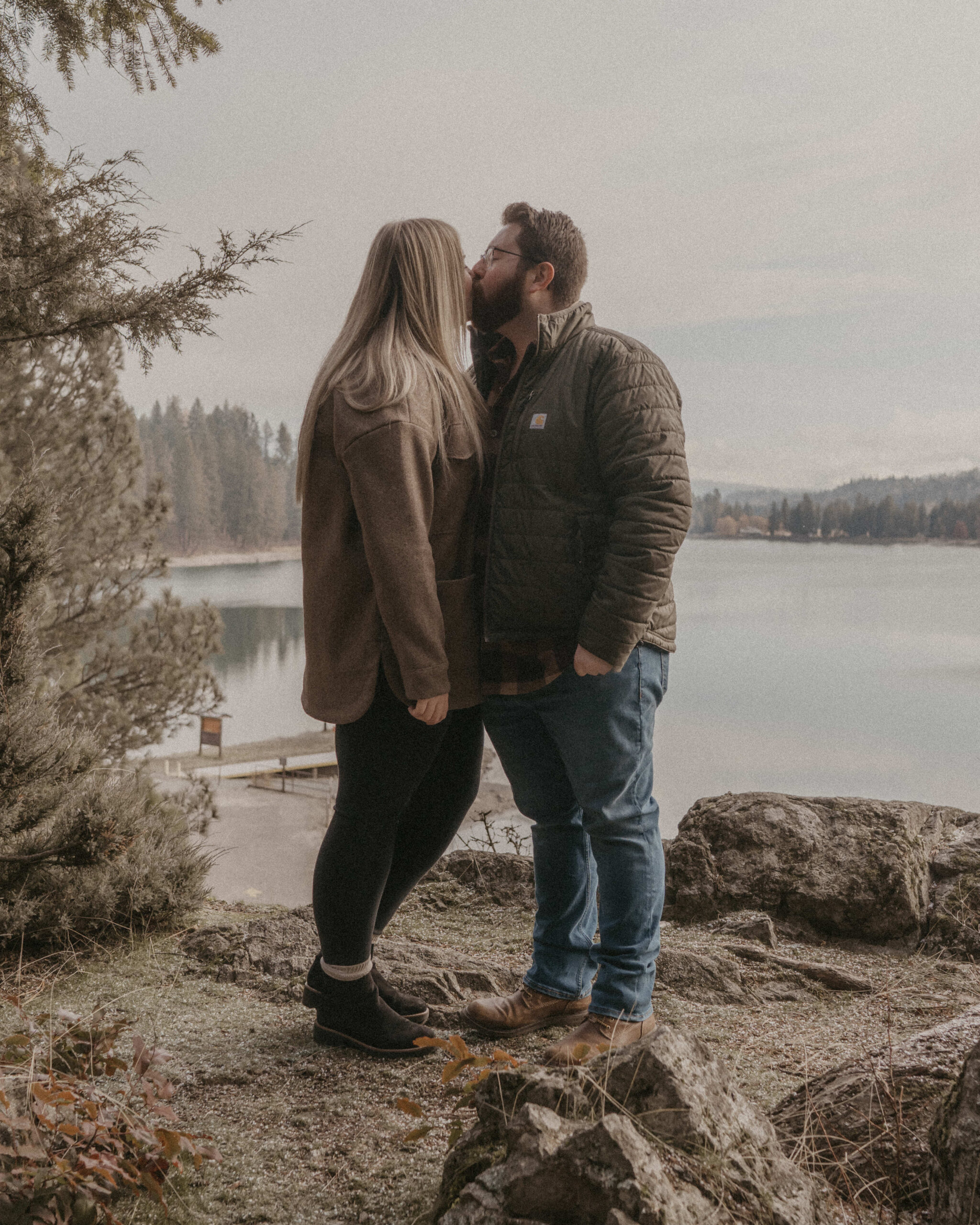 couple standing on a mountainside overlooking the river as they kiss