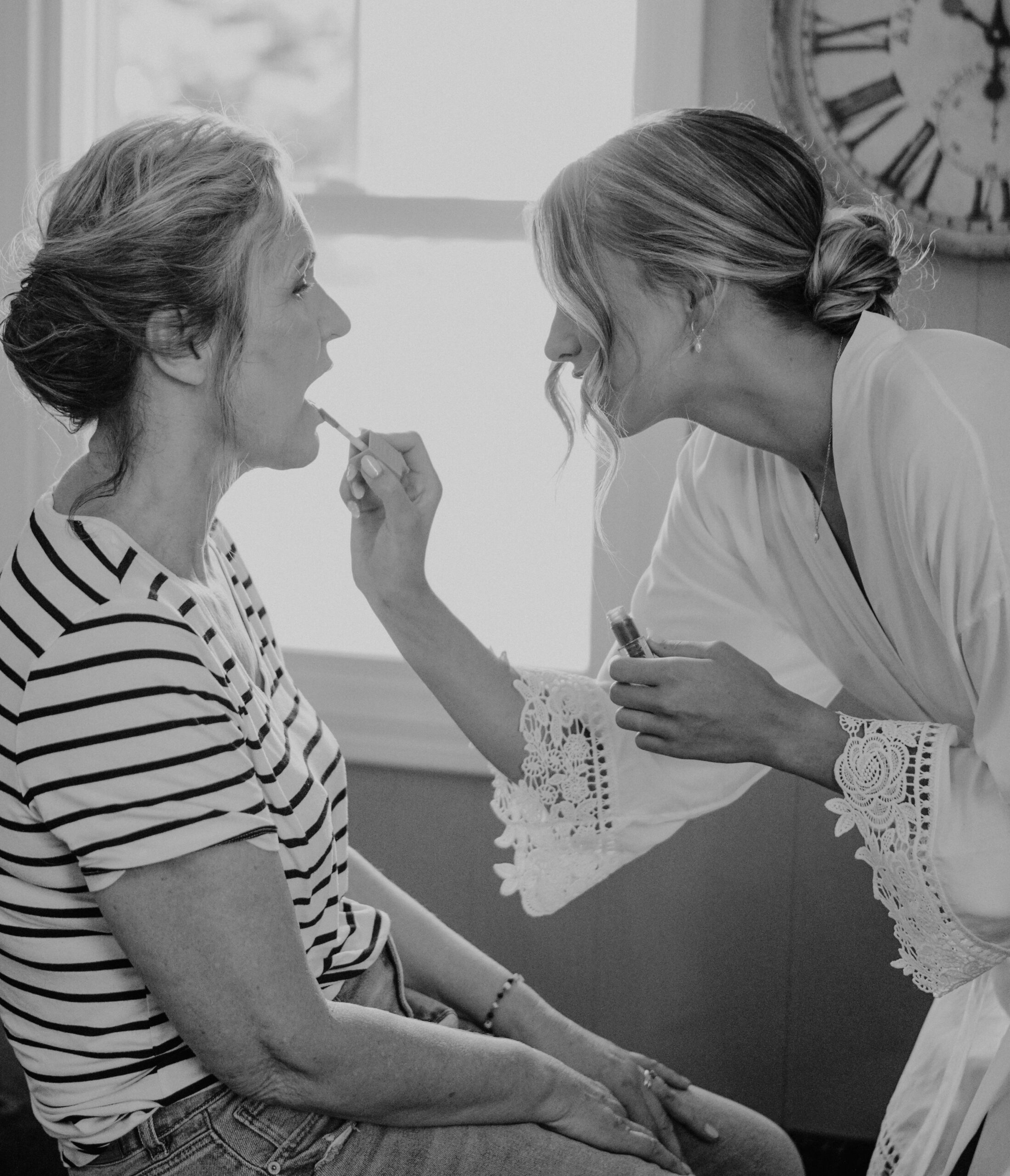 bride applying lipstick for her mom just before changing into her dress.