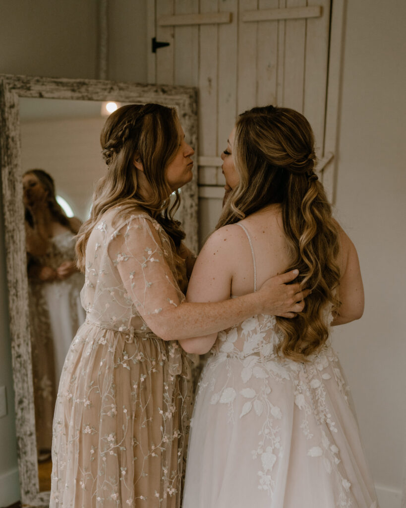 mom and bride sharing a moment after helping her daughter into her wedding dress.