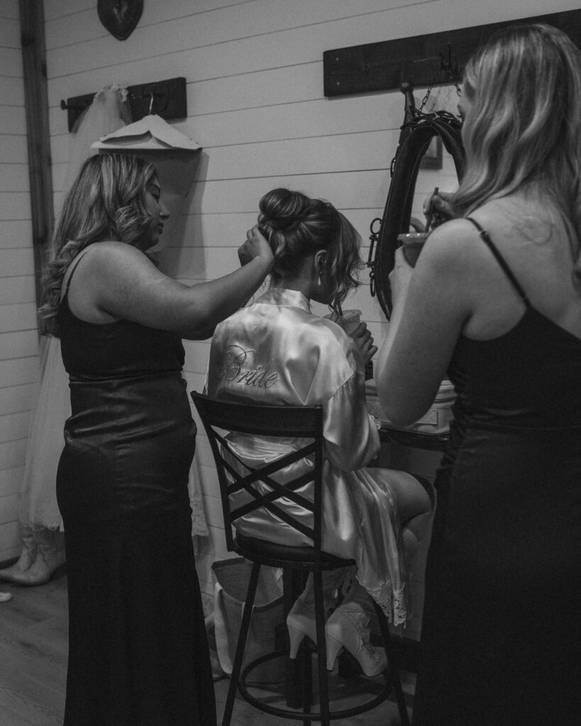 bride getting ready as her bridemaids help fix her hair