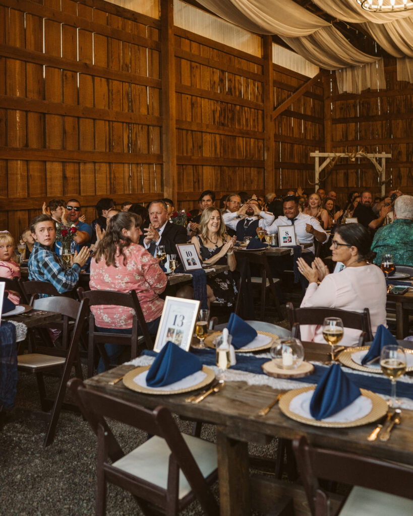 candid guests clapping just before the couple walk into the barn for dinner