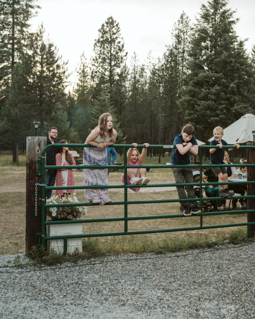 kids climbing the gate as they look on at people dancing. 