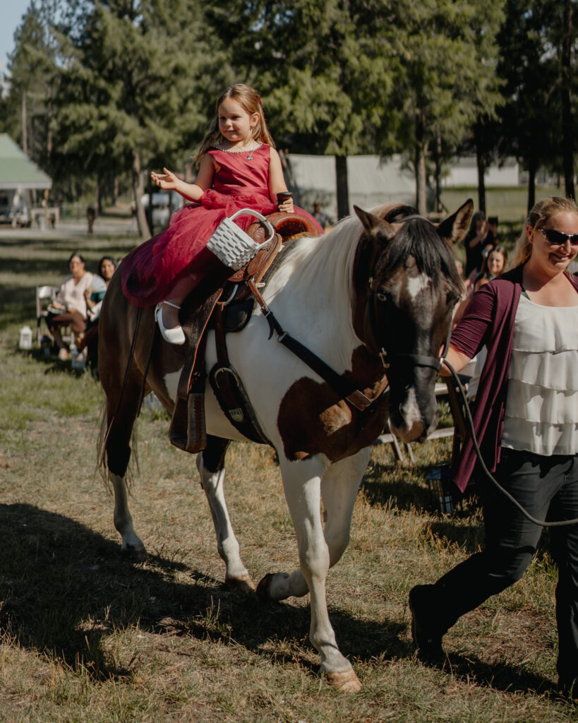 flower girl riding a horse up the aisle while tossing flowers