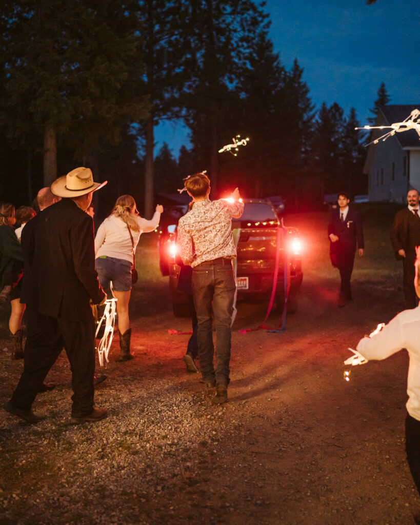 guests waving and throwing ribbon wands as the bride and groom drive away